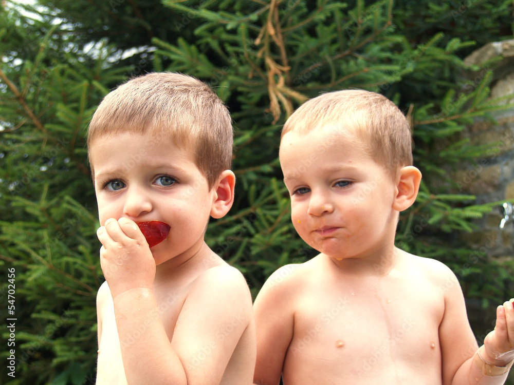 Two babies eat peach in garden Two babies eat peach in garden