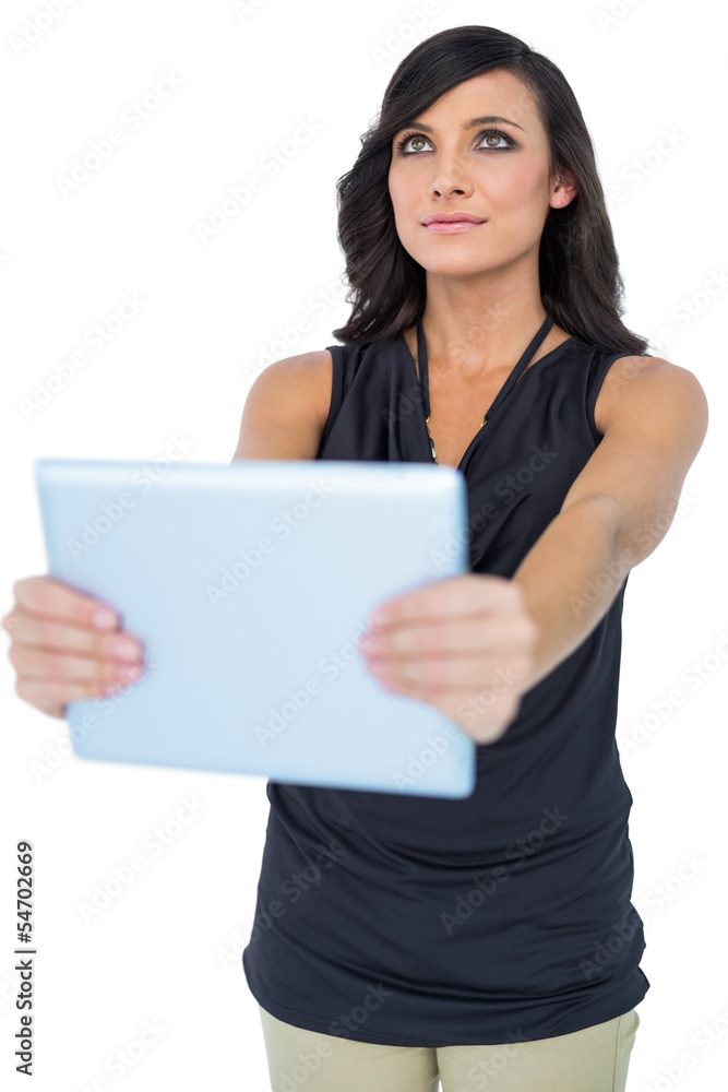 Elegant dark haired model holding tablet looking up Elegant dark haired model holding tablet looking up