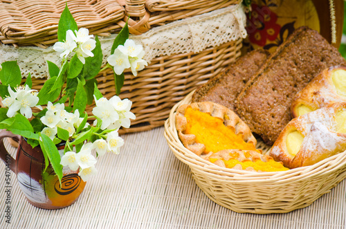 Buns in a wicker basket and a bouquet of jasmine flowers