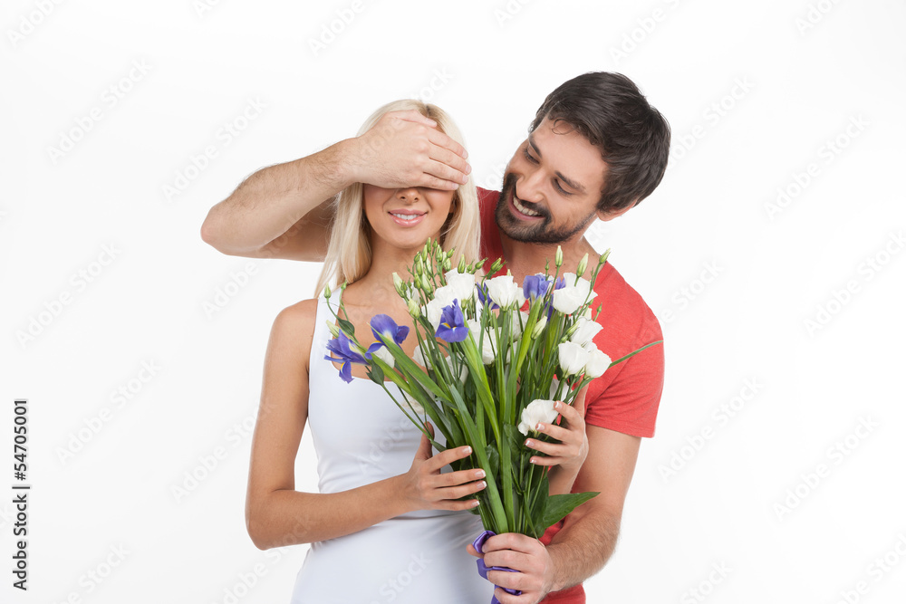 Surprise! Young cheerful men covering his girlfriend's eyes wit Surprise! Young cheerful men covering his girlfriend's eyes wit