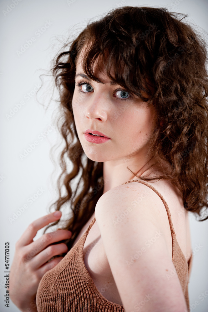 Beautiful young model with long curly hair posing in a studio