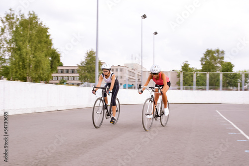 two female athletes competing in bike race outdoors.