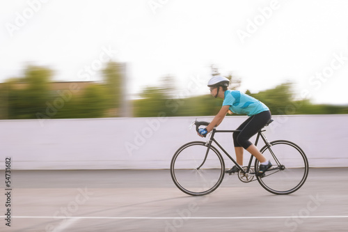 young female athlete racing on a bike. motion blurred image