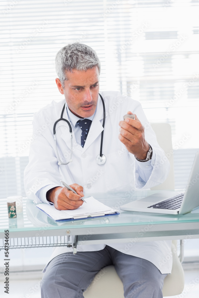 Serious doctor looking a medication for a prescription Serious doctor looking a medication for a prescription