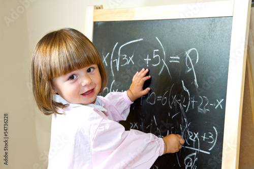 child draws with chalk on the blackboard photo