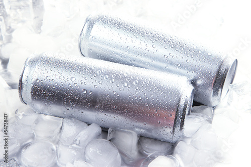 Metal cans of beer with ice cubes, close up