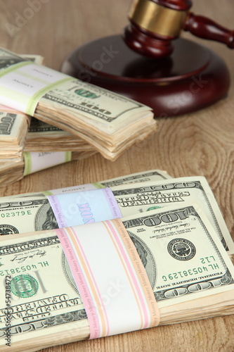 Stacks of money and judges gavel on wooden table