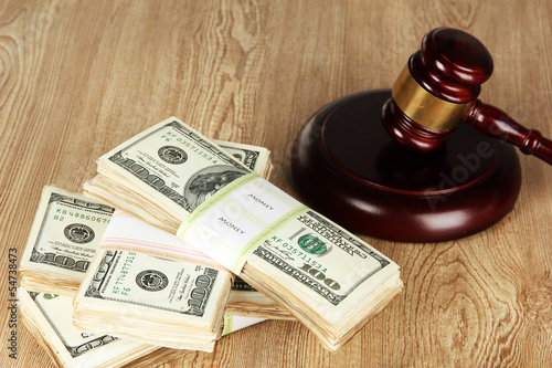 Stacks of money and judges gavel on wooden table