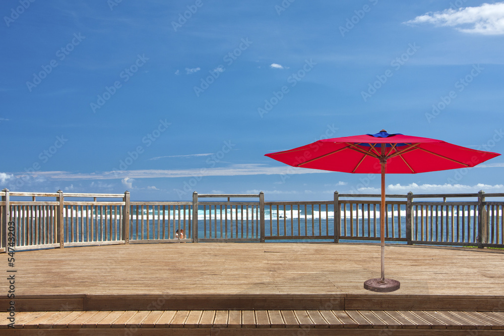 Fototapeta premium parasol rouge sur terrasse de bord de mer