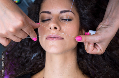 woman on facial hair removal threading procedure photo