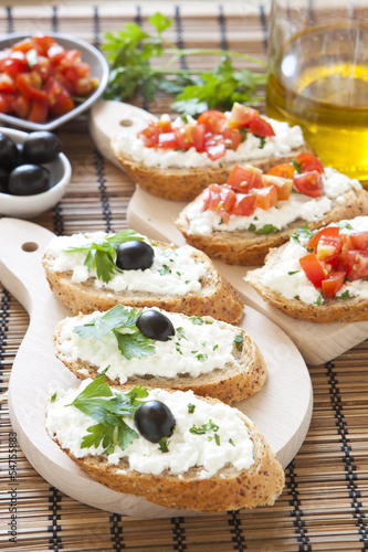 Crostini with cottage cheese, parsley, tomato and olives on cutt