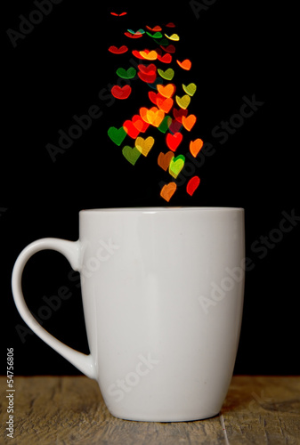 Bokeh heart spots of lights on background cup on wood