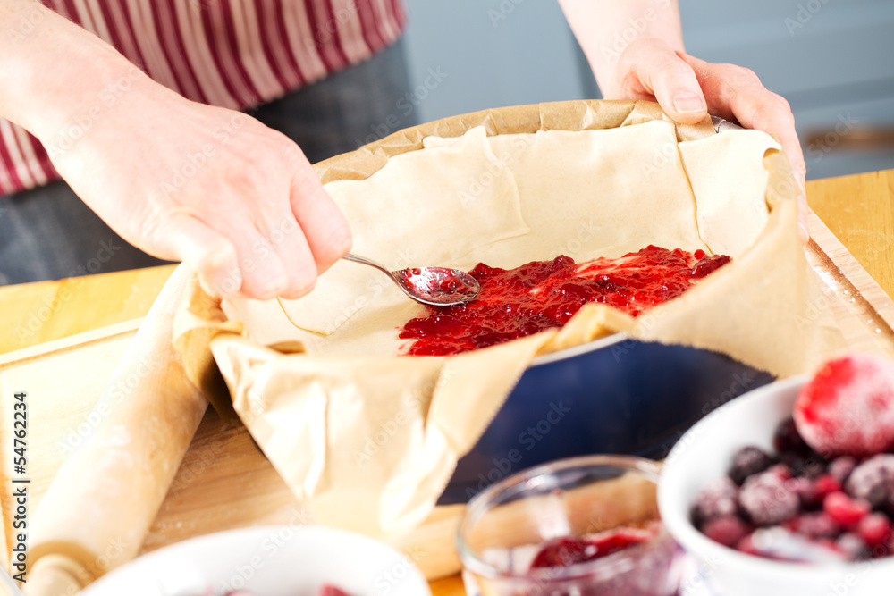 Cook spreading jam on pie dough