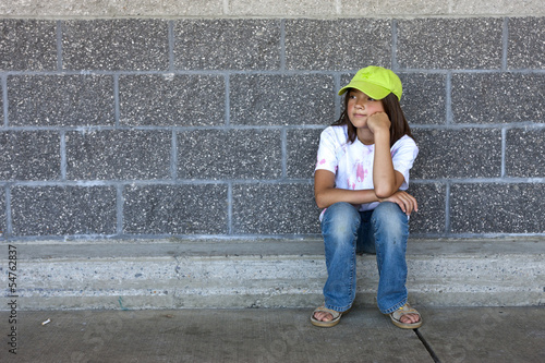Girl sits by a wall. © Gregory Johnston