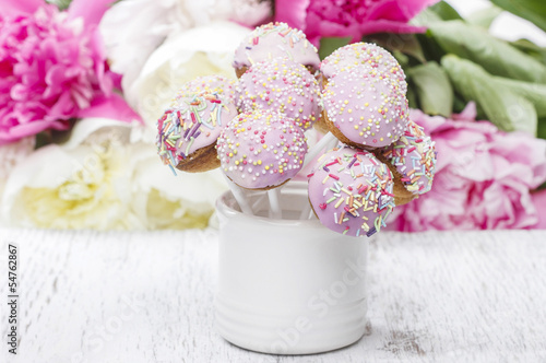 Pastel cake pops on rustic wooden table. Stunning peony flowers