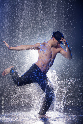 Dancing in the rain. Young male dancer in black fedora dancing i