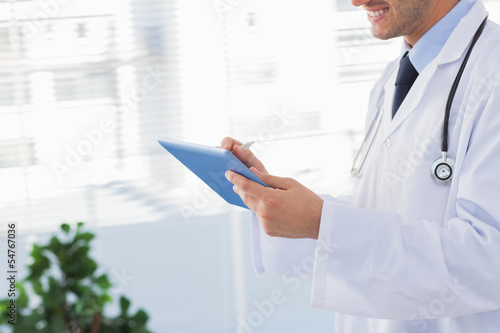 Smiling doctor using his tablet pc