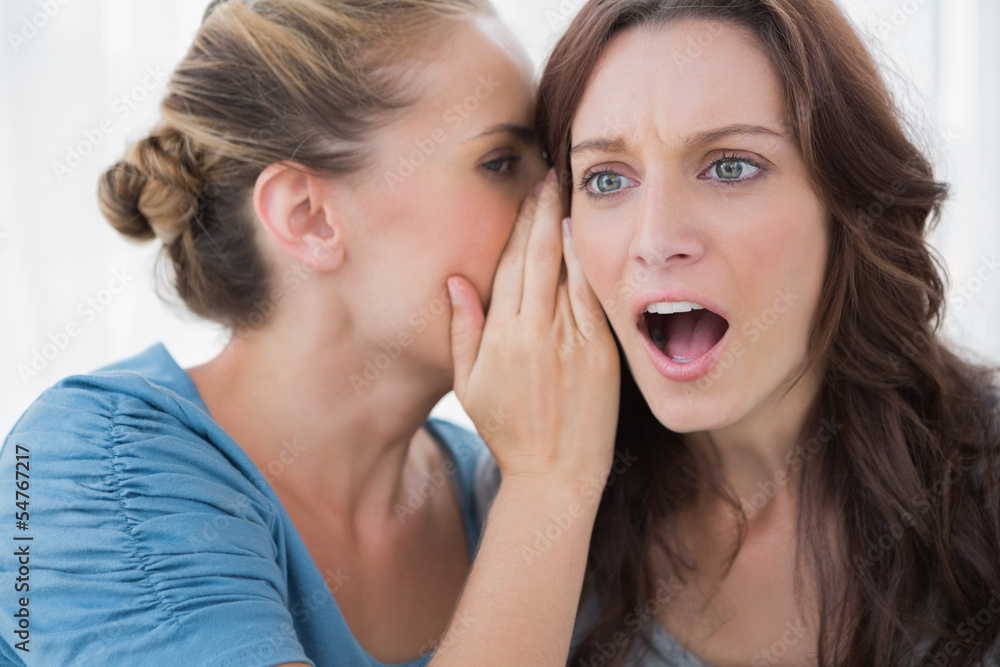 Stunned woman being told a secret by her friend Stunned woman being told a secret by her friend