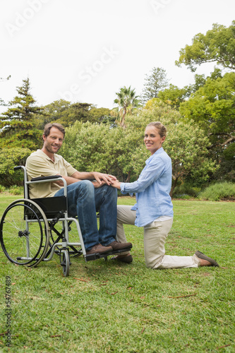 Attractive man in wheelchair with partner kneeling beside him