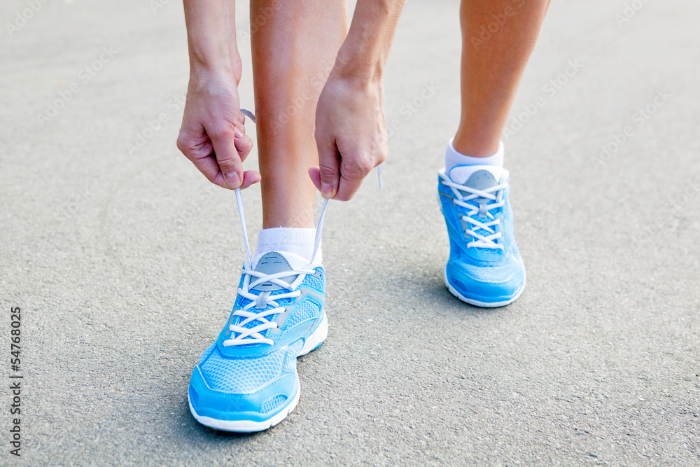 Closeup of Young Woman Tying Sports Shoe