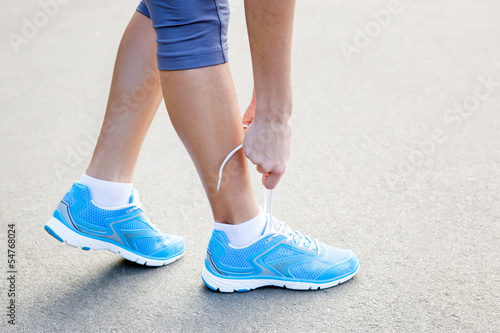 Closeup of Young Woman Tying Sports Shoe