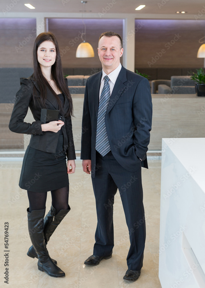 Man and woman in business suits standing at reception Man and woman in business suits standing at reception
