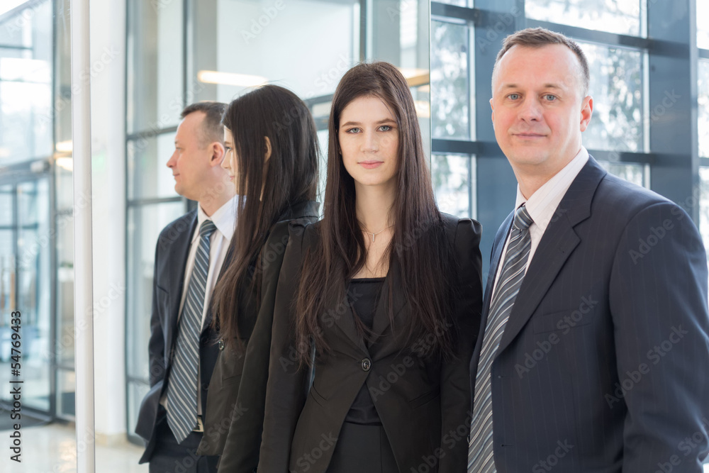 Serious man and woman in business suits stand near mirror Serious man and woman in business suits stand near mirror