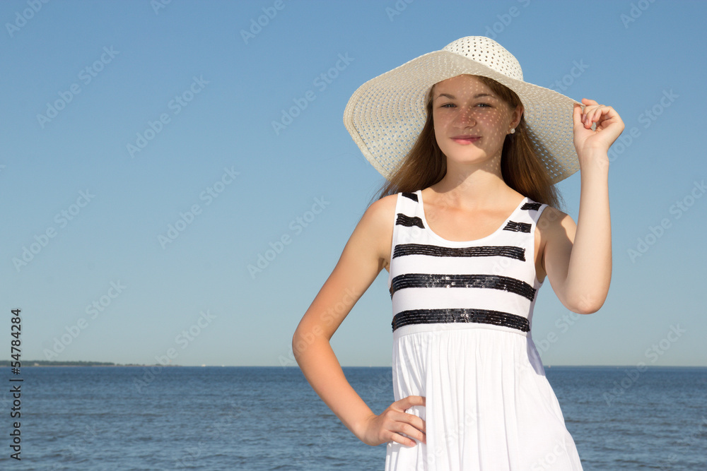 attractive woman in white dress and hat on the beach