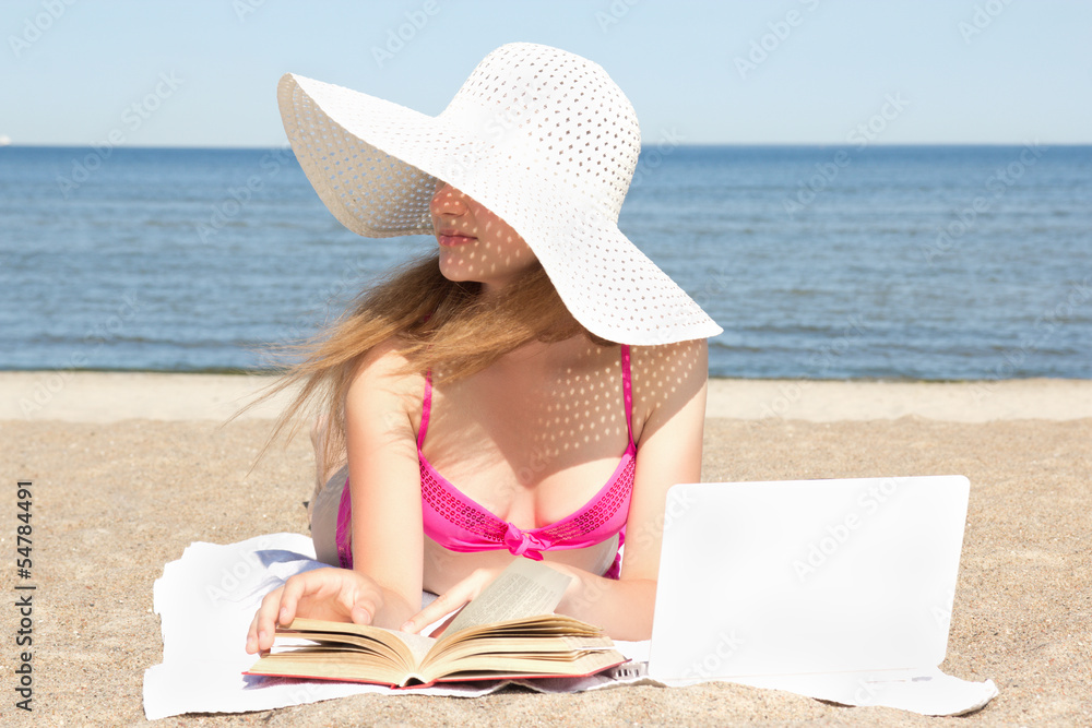female student with white laptop and book on the beach