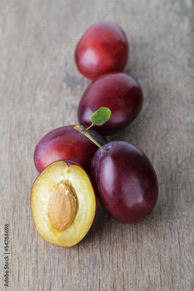 Fototapeta premium three ripe plums with leaves