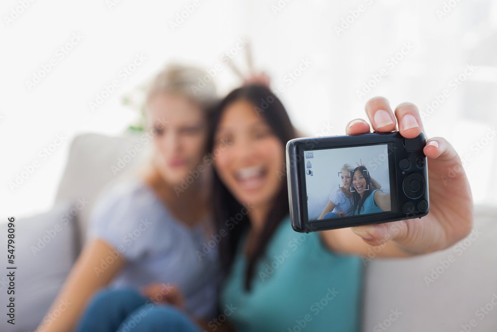 Two smiling friends taking photo with camera