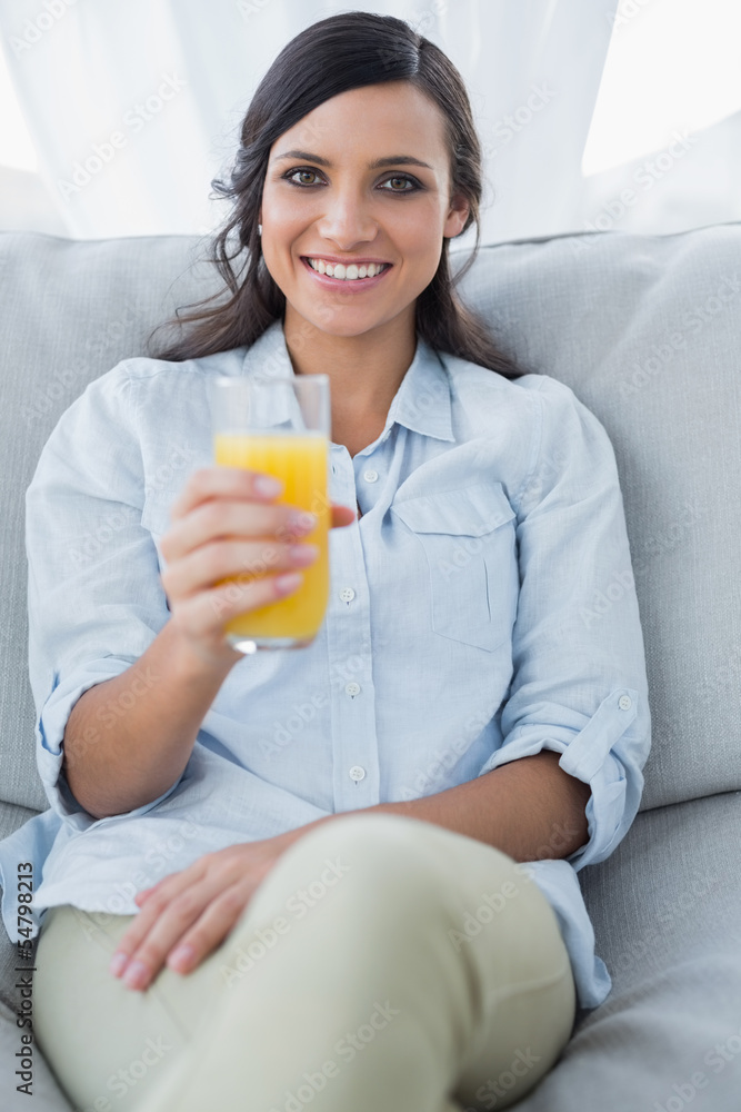 Smiling brunette offering orange juice to camera Smiling brunette offering orange juice to camera