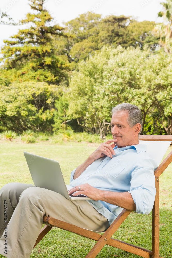 Man using laptop on sun lounger Man using laptop on sun lounger