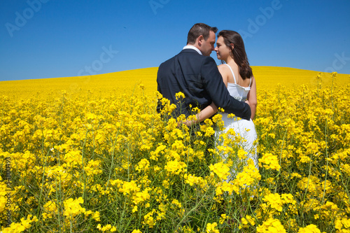 The loving couple  in the field in yellow flowers