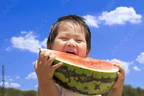 青空の下でスイカを食べる子供