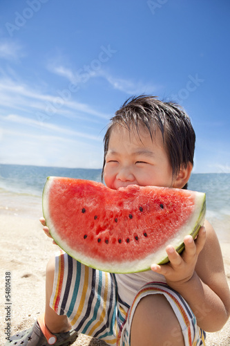 夏の海でスイカを食べる子供