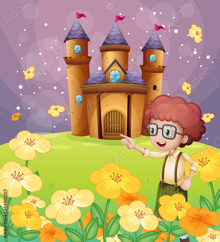 A boy pointing near the flowers in the hill with a castle