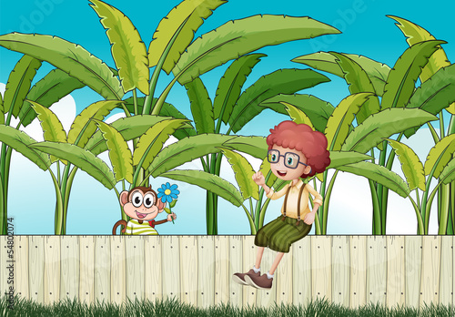 A boy sitting at the fence with a monkey