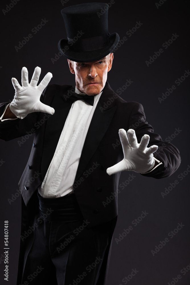 Magician making mysterious gestures. Wearing black suit and hat. Magician making mysterious gestures. Wearing black suit and hat.