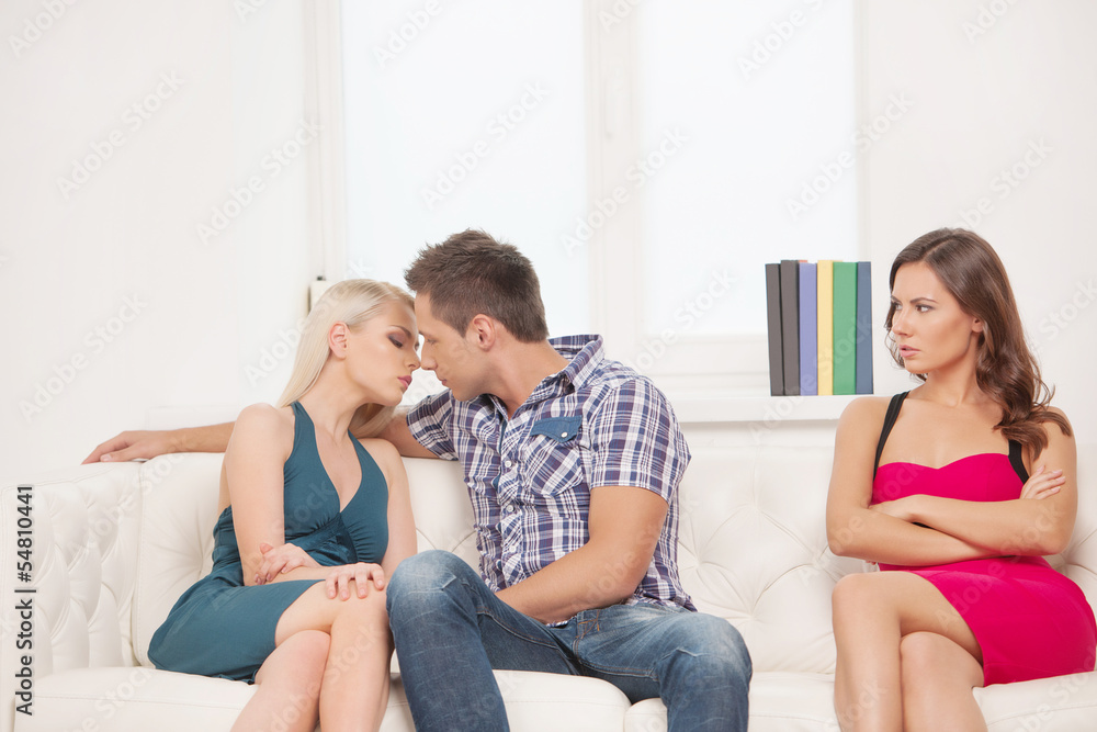 Jealousy. Young sad women sitting on the couch with her arms cro