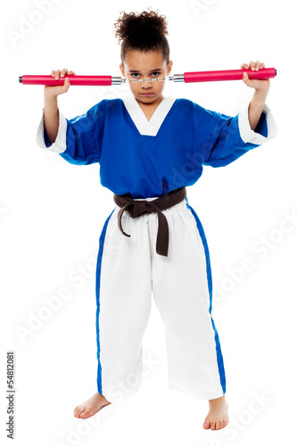 Young girl in karate uniform holding nunchucks