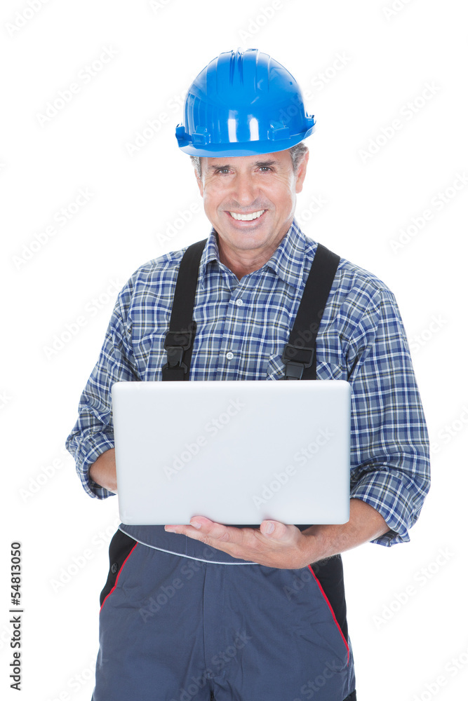 Worker wearing hard hat and using laptop Worker wearing hard hat and using laptop