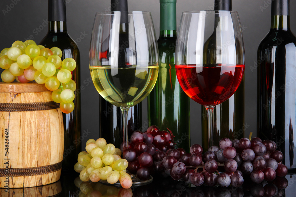 Assortment of wine in glasses and bottles on grey background