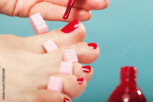 foot pedicure applying red toenails on blue