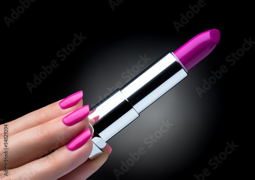 Woman hand with beautiful manicure holding pink lipstick