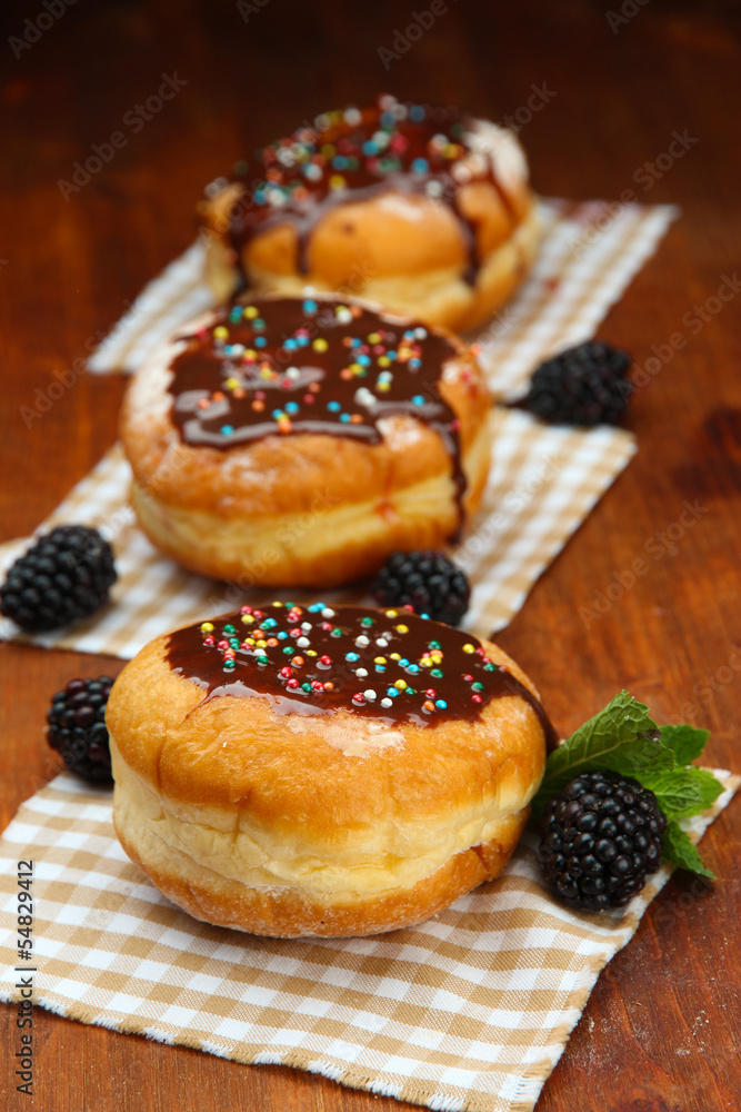 Tasty donuts with chocolate and berries on wooden table Tasty donuts with chocolate and berries on wooden table