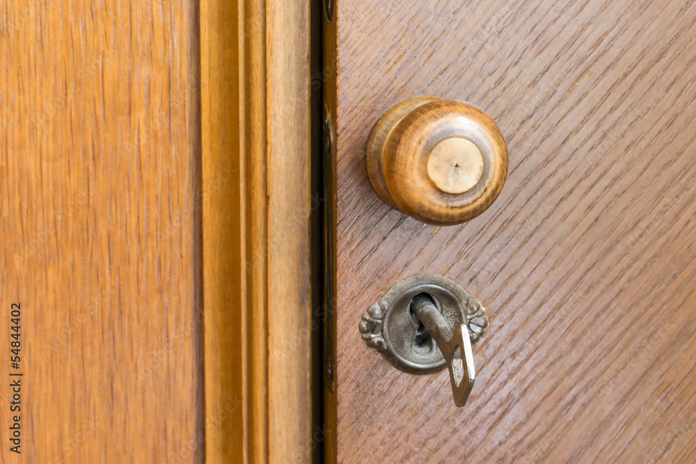 Wooden door handle and key in a keyhole Wooden door handle and key in a keyhole