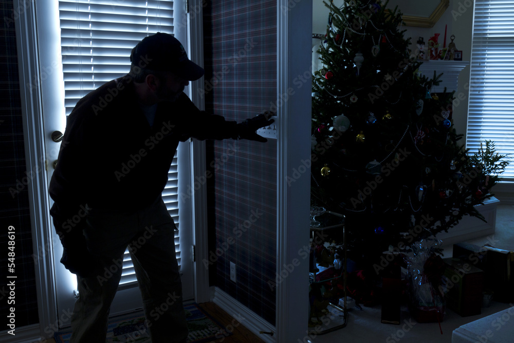 Burglar Breaking In To Home At Christmas Through Back Door - obrazy, fototapety, plakaty 