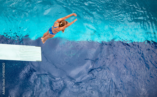 female springboard diver diving into the swimming pool
