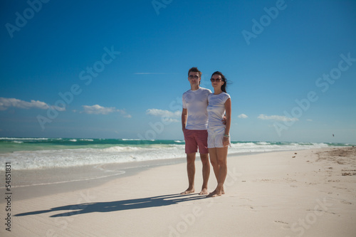 Young romantic couple walking on exotic beach in sunny day